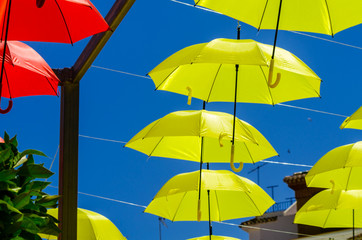 Fototapeta na wymiar Colourful umbrellas urban street decoration. Hanging colorful umbrellas over blue sky, tourist attraction
