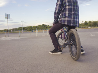casual teenage boy sitting chilling on bike on large asphalt sports ground