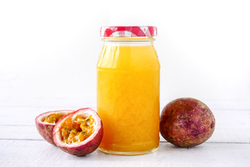 A bottle of juice and fresh passion fruit on wooden table.