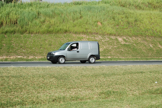 no brand mini silver delivery van slowly moving on road