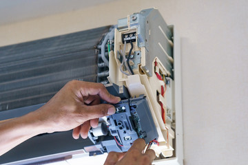 Technician repairing air conditioner with screwdriver, installation electric wires of the air conditioner