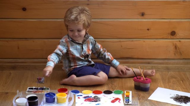 Creativity and education concept. Drawing. Happy cute boy colors his hands. Doing Finger painting. Art therapy for children. Psychology of the child's personality