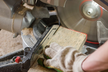 Saw the board. The man saws the board with an electric saw. Joinery.