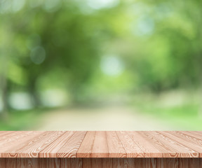 Wood table top on blur green background of trees in the park - can be used for display or montage your products