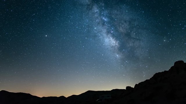 Milky Way to sunrise time lapse RV camper in rocky canyon Mojave Desert California