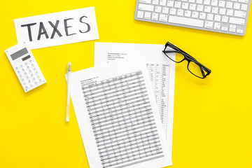 Pay taxes concept. Taxes word on office work desk with keyboard and calculator on yellow background...