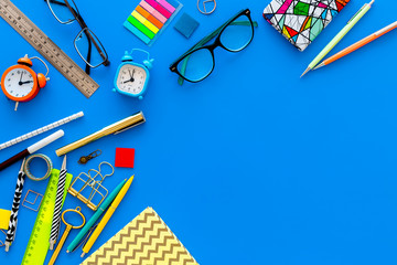 Education concept. Stationery for school pupil mockup with glasses and notebook on blue background top view copy space
