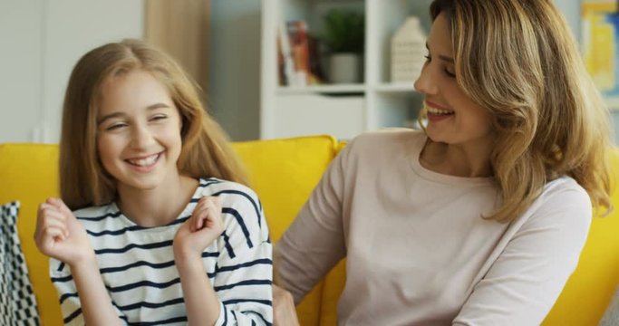 Portrait shot of the laughing cute girl with her mother who tickling her in the living room. At home. Indoor.