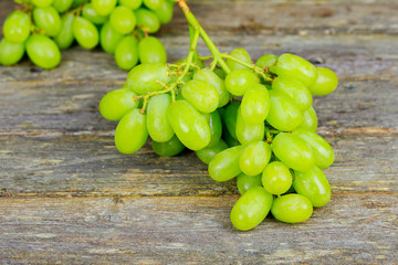 Bunch of green grapes in fruits of autumn, a symbol of abundance on rustic wood background