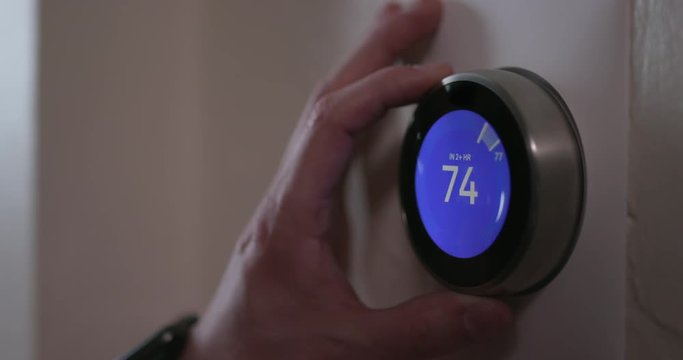 Man Turning Down Temperature of Smart Thermostat Gadget At Home - Close
