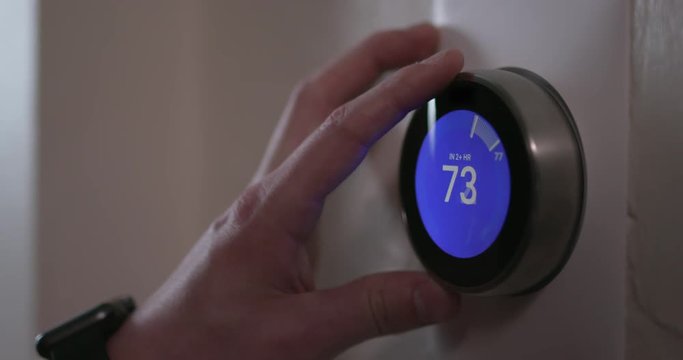 Man Turning Up Temperature of Smart Thermostat Gadget At Home - Close