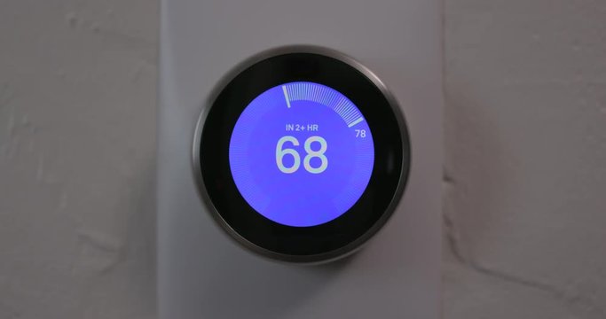 Man Decreasing Temperature of Smart Thermostat Gadget At Home - Medium