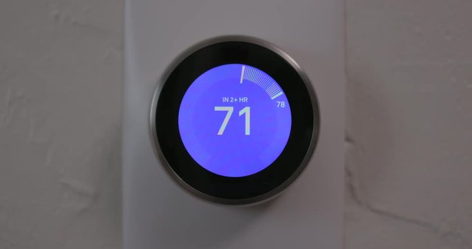 Woman Adjusting Temperature of Smart Thermostat Gadget At Home - Close
