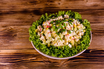 Ceramic plate with salad from crab sticks on wooden table