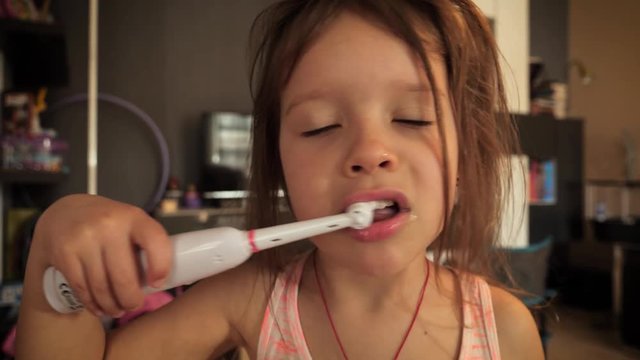 Cute little child girl portrait brushing teeth in the morning at home