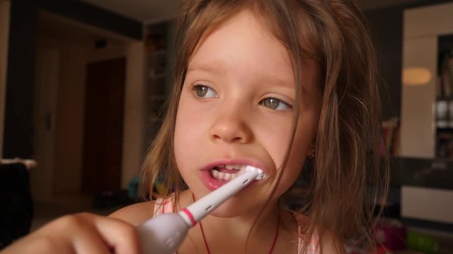Cute little child girl portrait brushing teeth in the morning at home