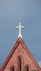 Cross on top of gable of church roof on blue sky background at cathedral of the holy trinity, the church of the province of Myanmar.