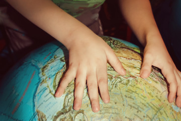 Children's hands touch the big globe