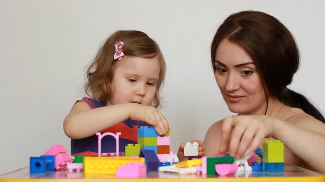 Mother and girl child busy building a constructor.