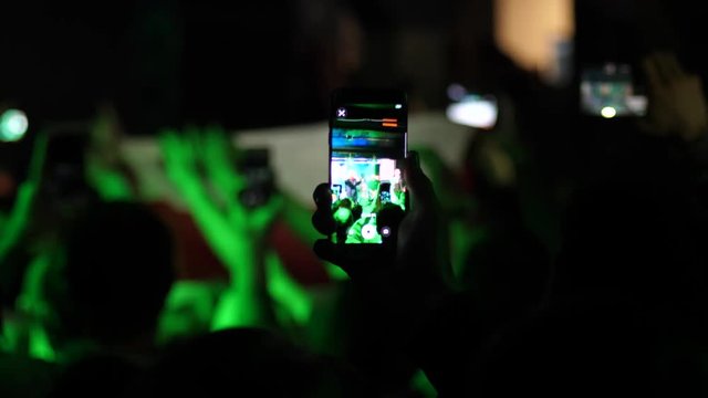 Smart phones in hands spectators crowd shoot video of concert performance