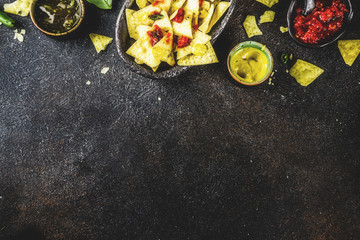 Mexican food, nachos snack with salsa and sauces on dark rusty background top view copy space