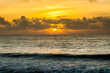 Dramatic sunset sky with clouds over ocean.