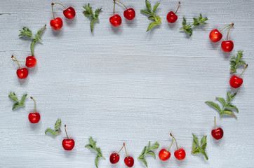 Cherries and mint leaves with copy space for text in the centre on the gray concrete background. Top view