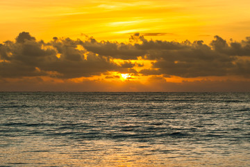 Dramatic sunset sky with clouds over ocean.