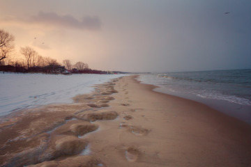 Beach covered by ice with footprints on the sand