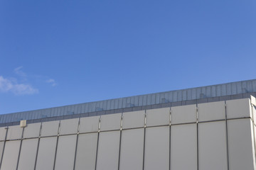 Facade of a concrete slab building on an angle against a blue sky, horizontal aspect