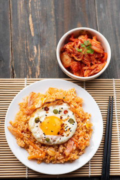 Kimchi fried rice with fried egg on top and fresh kimchi cabbage in a bowl, Korean food