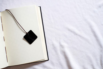 Top view collection of black leather notebook and bookmark with grid paper on white background