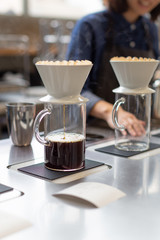 The proccess of hand dripping coffee in the coffee shop. Barista on the background.