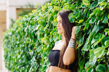 pretty woman leaning against an ivy wall