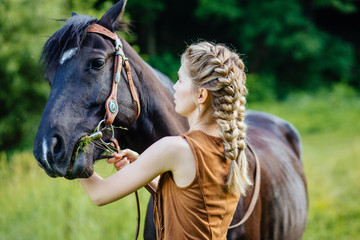 Obraz premium Young teenage blond girl equestrian talking with her chestnut horse. Multicolored outdoors horizontal image.