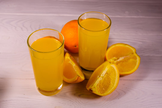 Oranges and glasses with orange juice on a wooden table
