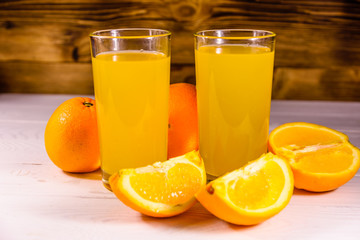 Oranges and glasses with orange juice on a wooden table
