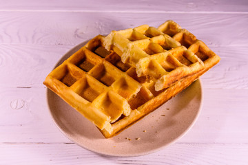 Ceramic plate with belgian waffles on wooden table