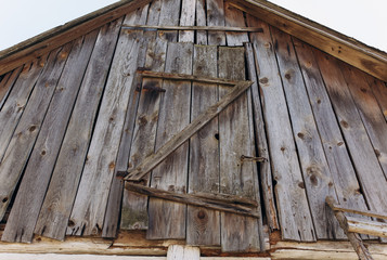Attic roof dorrs with wooden grey natural vertical planks with holes. Old rustic texture.