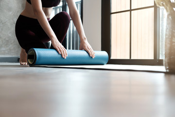 Yoga Woman rolling her lilac mat after a yoga class