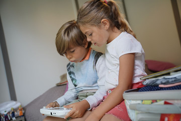 KIds playing video game sitting on bed © goodluz