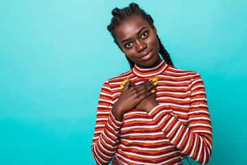 Young woman showing her heartfelt gratitude and thanks clasping her hands to her heart with a pleased smile isolated on green background