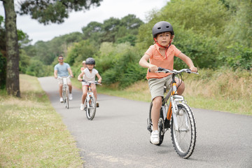 Kids with parents riding bikes in countryside