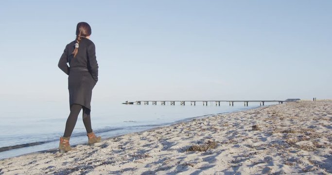 Woman walking at Copenhagen Amager Strand Beach and Oresund.