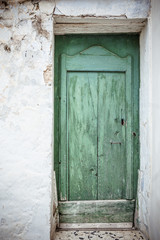 Front door. Old greenish blue wooden door and weathered dirty wall