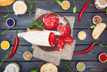 Sliced cured coppa with spices and a sprig of rosemary.