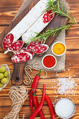 Sliced cured sausage with spices and a sprig of rosemary.