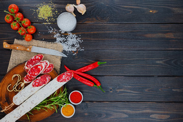 Sliced cured sausage with spices and a sprig of rosemary.