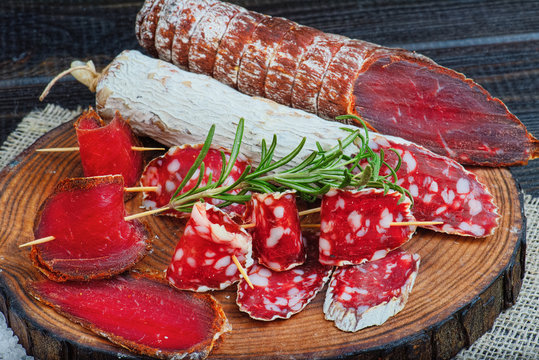 Sliced cured sausage and bresaola with spices and a sprig of rosemary.