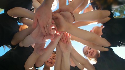 Group of school kids performs sports motivational greeting with hands on playground of yard football at sunny day - Powered by Adobe